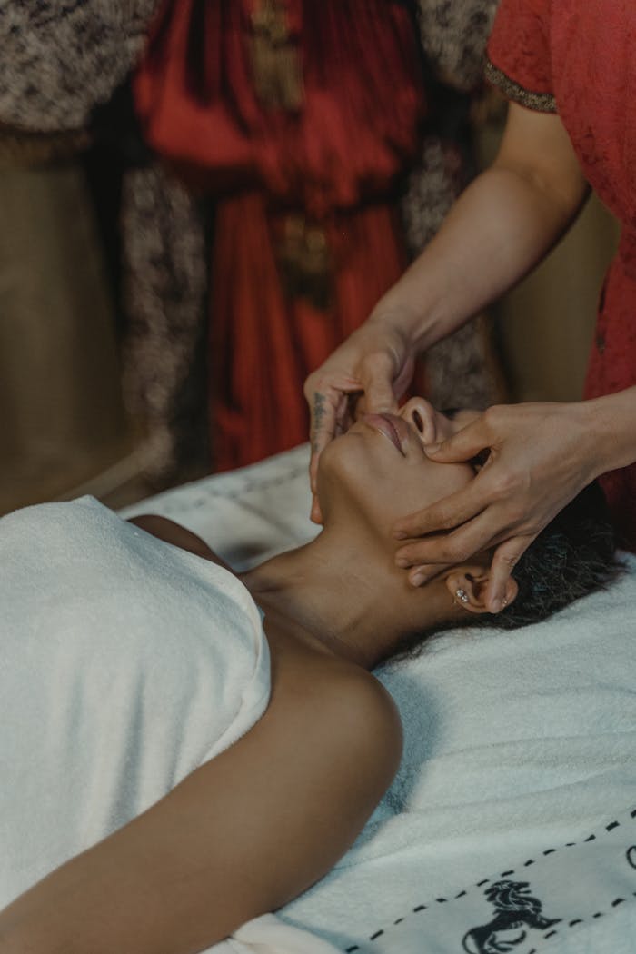 Woman Lying on Bed Having a Facial Massage